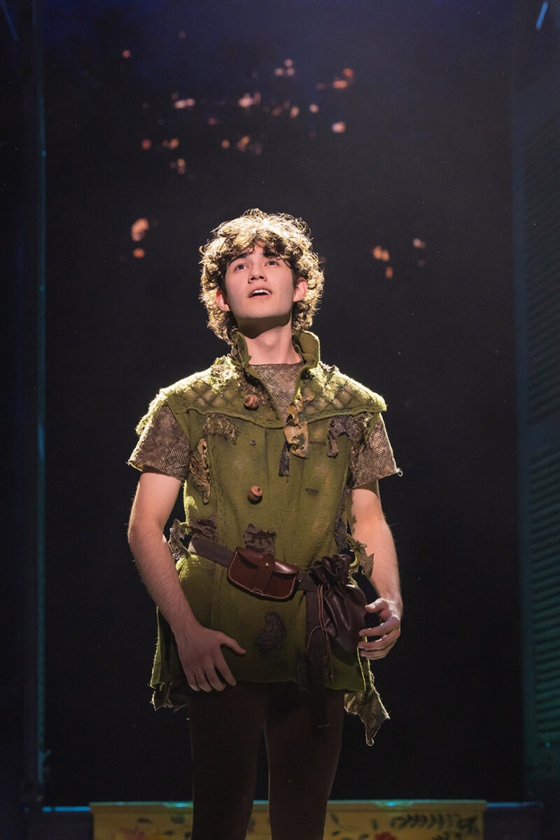 Nolan Almeida as Peter Pan. Peter Pan, in his signature green, looks up with an expression of hope as he sings.