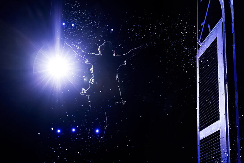 Nolan Almeida as Peter Pan in Peter Pan. Peter Pan flies out of the window of the Darling house into a starry night sky.